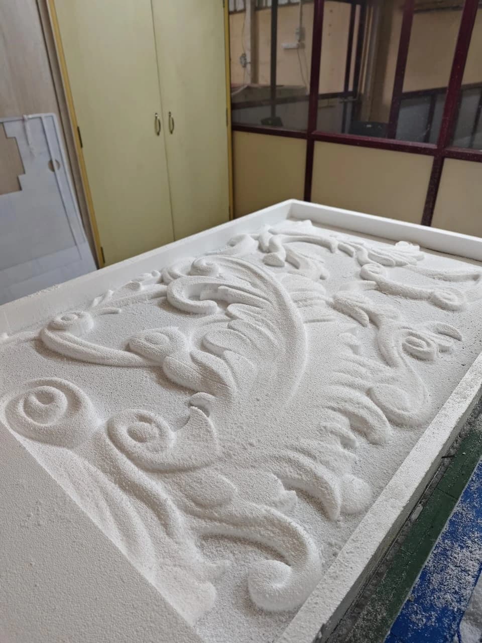 CNC-routed ornamental floral scroll relief carving on foam panel at DL Enterprises workshop